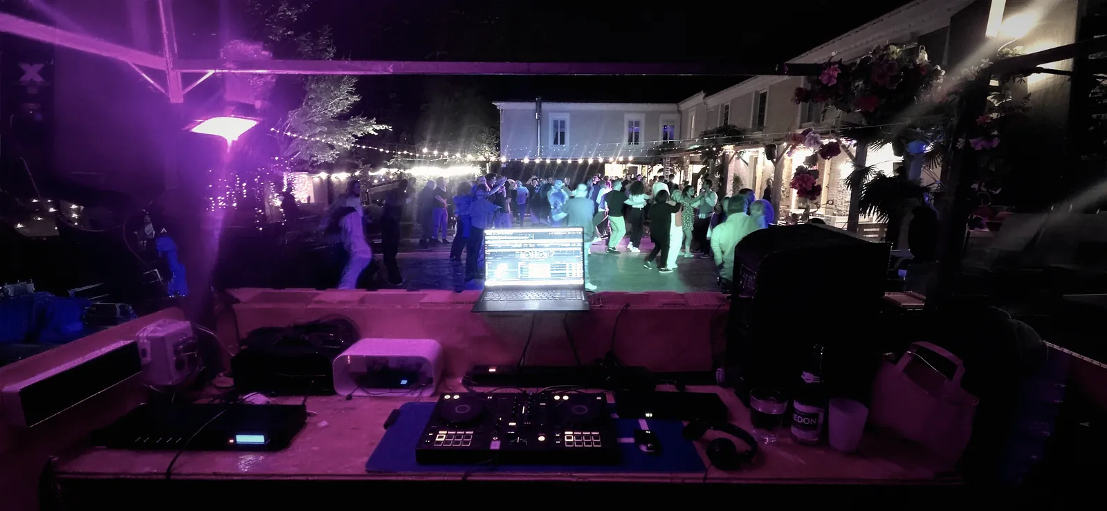 Piste de danse pleine sous les lumières roses, vue depuis la cabine du DJ